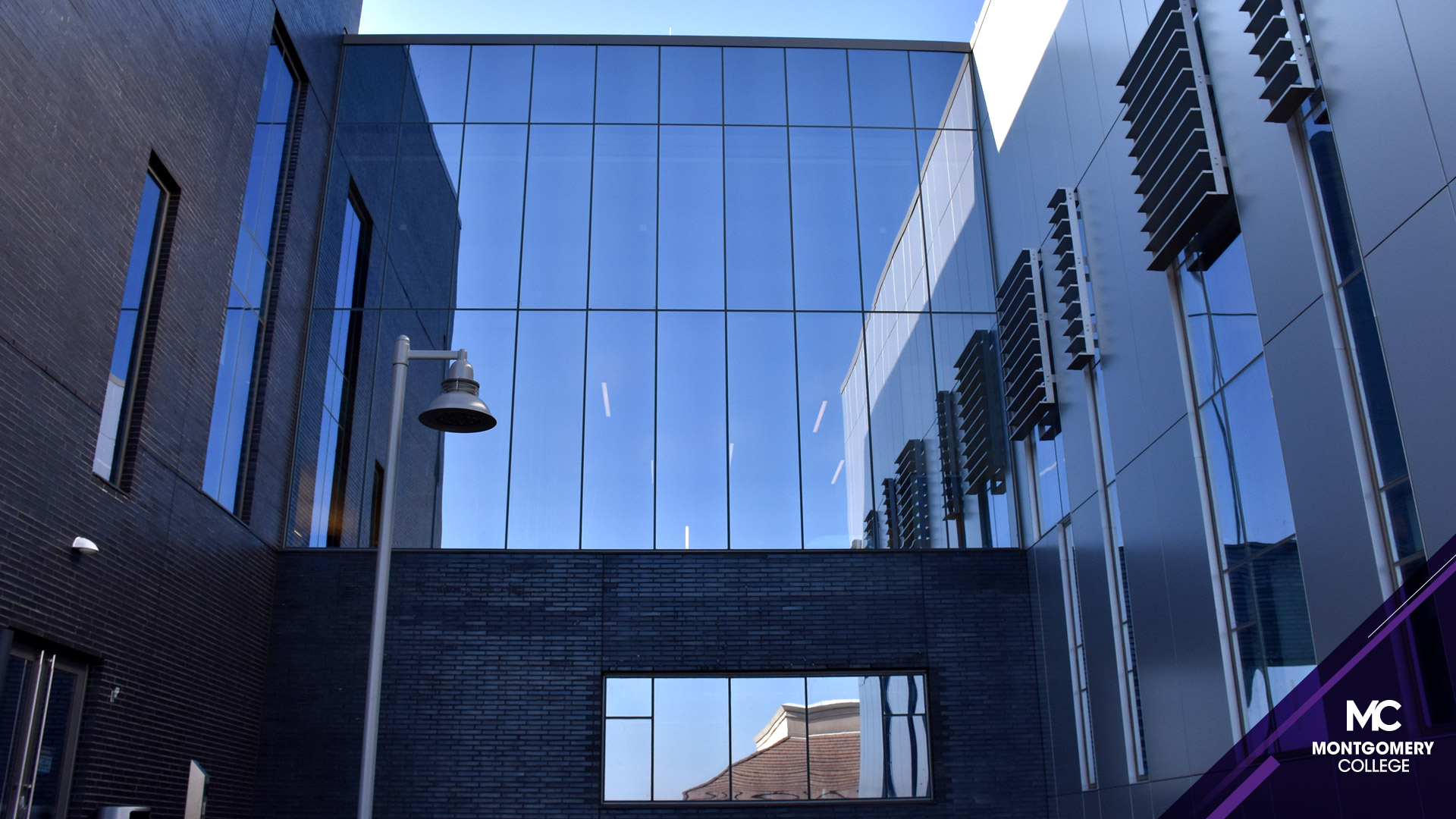 明亮的蓝天反射在日耳曼敦校区学生事务和科学大楼外的镜面玻璃上。