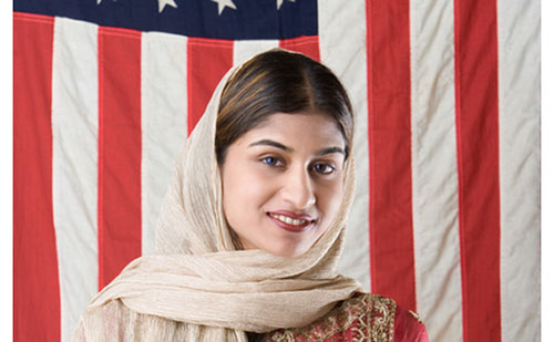 Woman wearing head scarf in front of the flag of the United States of America