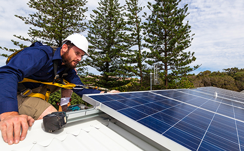 Worker installing solar panels on a roof
